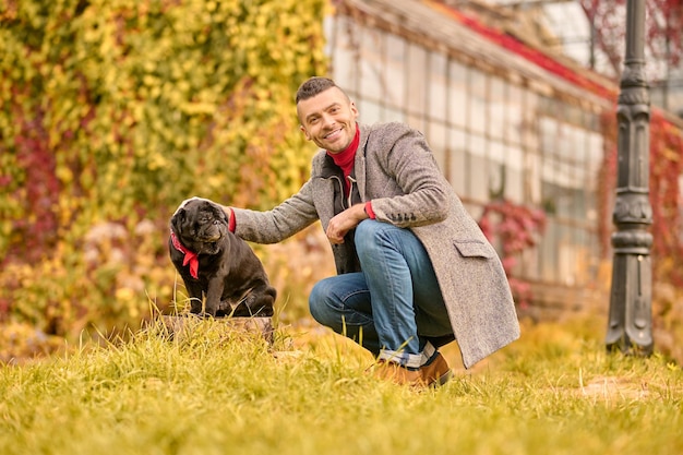 Um homem com um cachorro preto no parque de outono