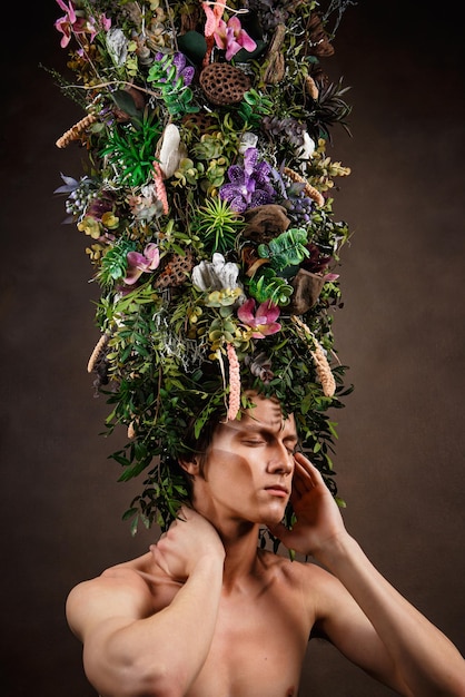 Foto um homem com um enorme cocar alongado feito de vegetação diversa viva e flores um filho da natureza uma criatura fabulosa objeto de arte