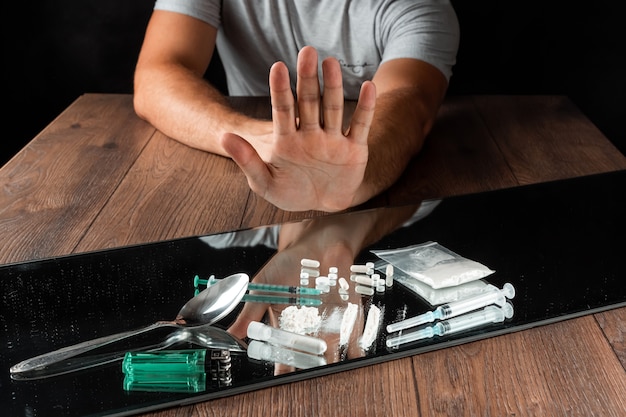 Um homem com um gesto de parada recusa drogas. A luta contra a toxicodependência.