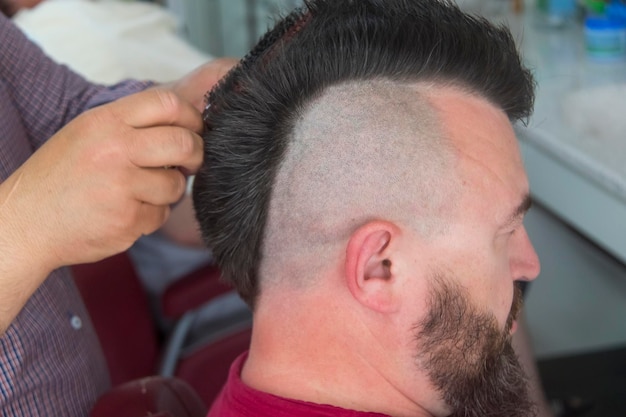 Um homem com um moicano e barba na barbearia