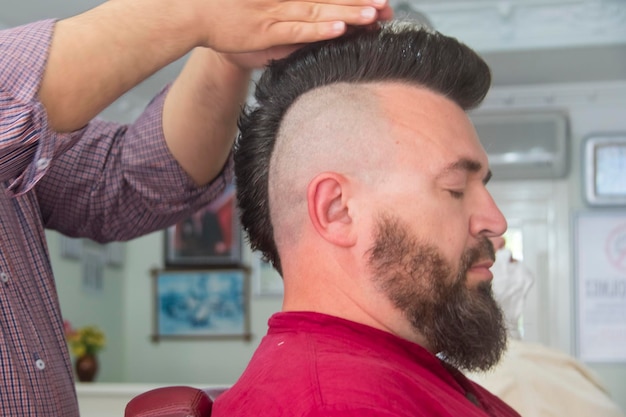 Um homem com um moicano e barba na barbearia