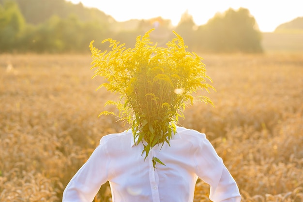 Um homem com um rosto escondido atrás de um buquê de flores em um campo despersonalização Foco suave