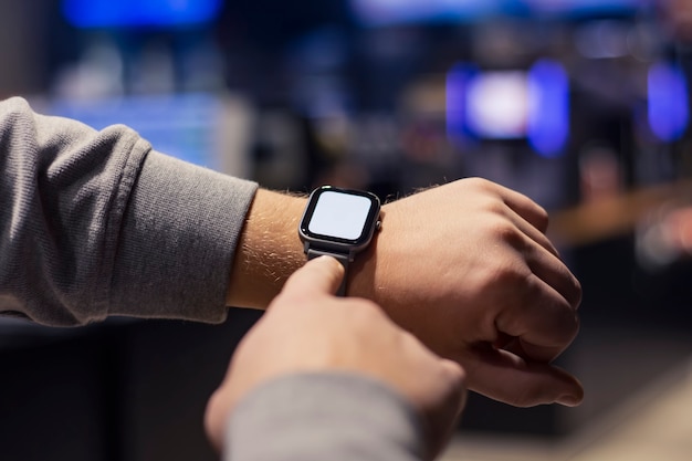 Foto um homem com um smartwatch e uma maquete de tela branca na mão. um homem usa um rastreador de fitness no fundo de um shopping.