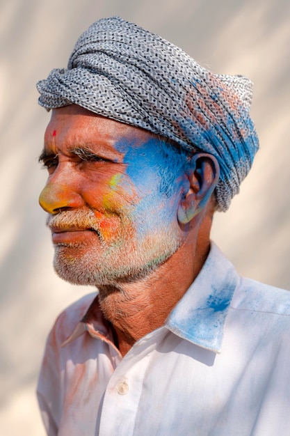 Foto um homem com um turbante na cabeça está coberto com as cores do festival holi.