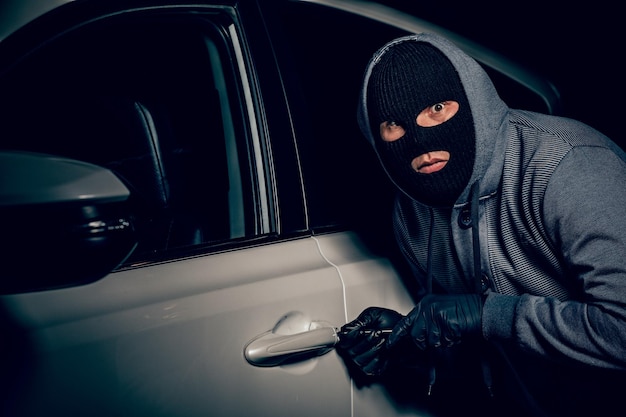 Um homem com uma balaclava na cabeça tentou entrar no carro Ele usa uma chave de fenda