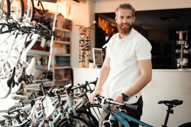 Um homem com uma barba posando com uma bicicleta.