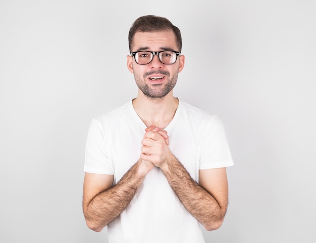 Um homem com uma camiseta branca pendurada na parede cinza faz um pedido de aniversário.