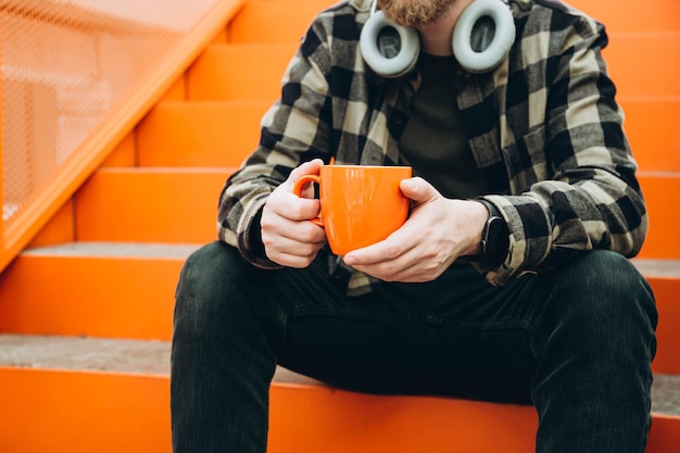 Um homem com uma chávena durante uma pausa para café Um trabalhador de escritório está sentado nas escadas