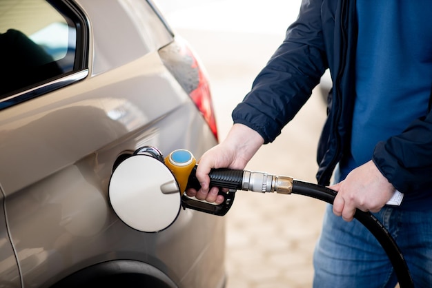 Um homem com uma jaqueta azul e óculos escuros em um posto de gasolina Ele enche o carro Gasolina Lifestile