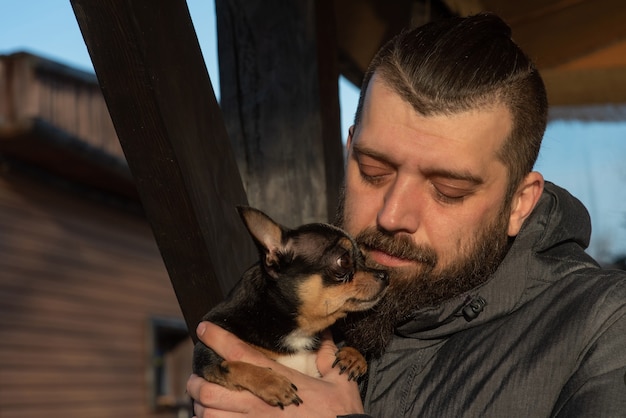 Um homem com uma jaqueta com um cachorro chihuahua.