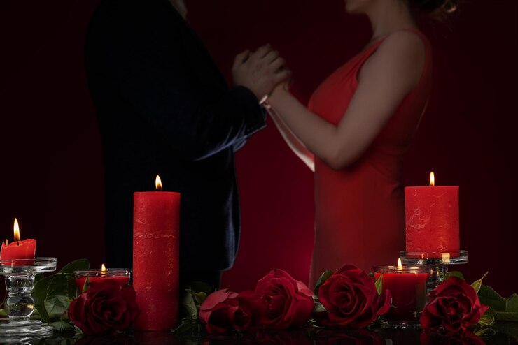 Foto um homem com uma jaqueta e uma mulher com um vestido vermelho estão de mãos dadas, velas e rosas luxuosas