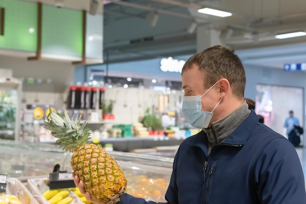 Um homem com uma máscara facial protetora com um abacaxi na mão Estilo de vida em quarentena Alimentos e bebidas