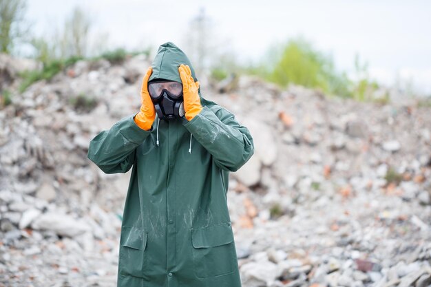 Um homem com uma máscara protetora e roupas de proteção explora a zona de perigo Foco seletivo de catástrofe ecológica