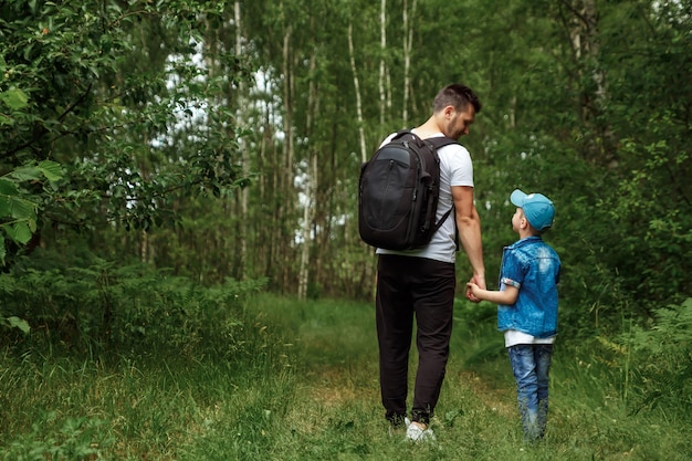 Um homem com uma mochila, um pai e seu filho em uma caminhada, andando durante caminhadas na floresta.