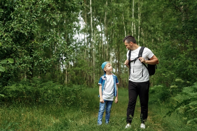 Um homem com uma mochila, um pai e seu filho em uma caminhada, andando durante caminhadas na floresta.