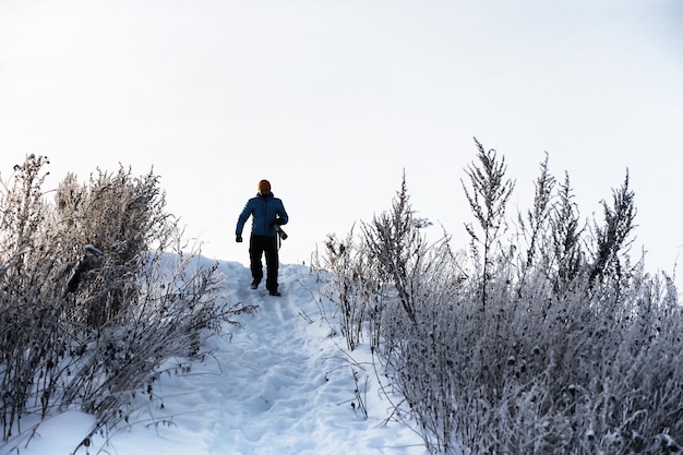 Um homem com uma mochila viaja no inverno Um homem em um campo nevado Caminhando na paisagem de inverno