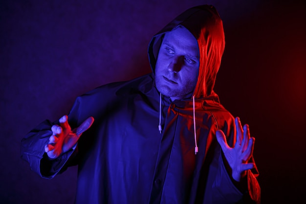 Um homem com uma roupa de proteção em um quarto escuro. Conceito de imagem de Halloween. Proteção contra vírus. Iluminado com luzes coloridas