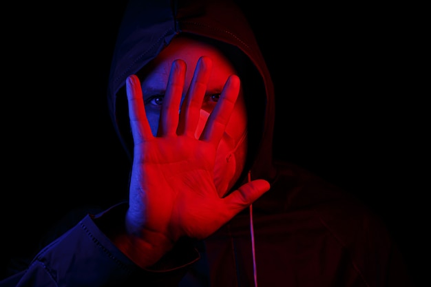 Um homem com uma roupa protetora de borracha e uma máscara médica branca. Proteção contra vírus. Iluminado em vermelho e azul.