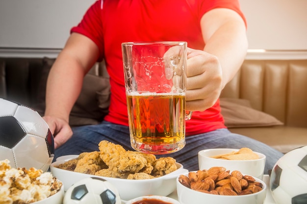 Um homem come lanches e bebe cerveja em casa