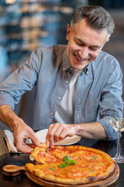 Um homem comendo pizza e parecendo animado