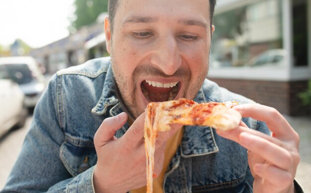 Um homem comendo uma fatia de pizza