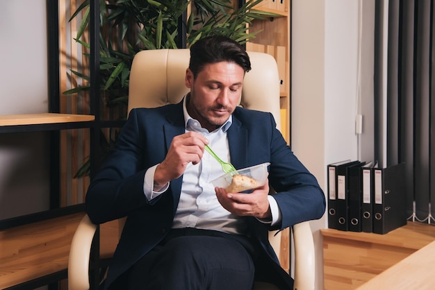 Um homem comendo uma tigela de comida em um escritório