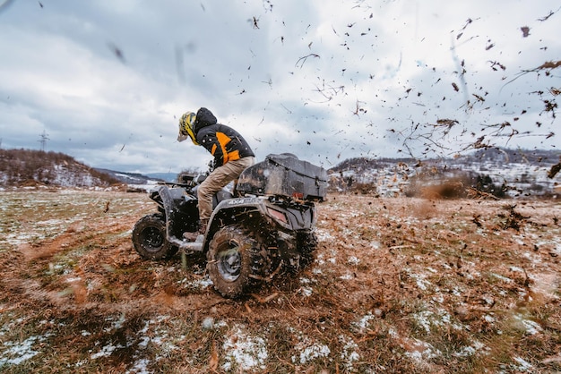 Um homem conduz um ATV na deriva de lama conduzindo um ATV quad na lama e na neve