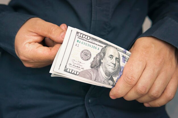 Um homem considera notas de dólar em um fundo escuro, conceito de independência financeira