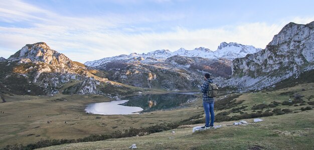 Um homem contempla o lago Ercina com montanhas nevadas atrás nas Astúrias (Espanha)