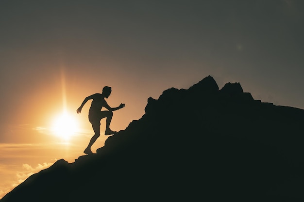 Um homem corre entre as rochas em um pôr do sol colorido da montanha