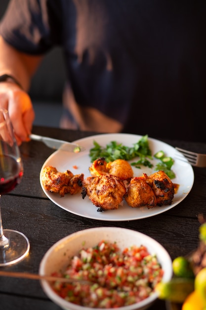 Um homem corta a carne com uma faca, o homem come carne grelhada, comida kebab, salada, carne com ervas