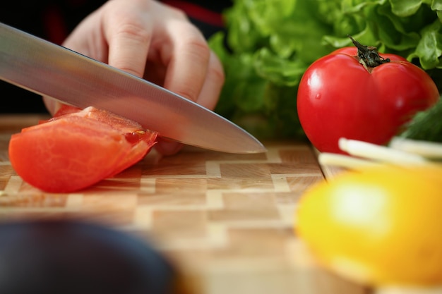 Um homem corta a carne de um tomate vermelho com uma faca