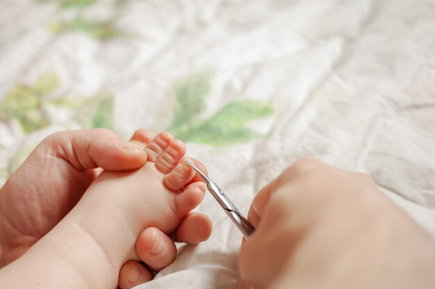 Um homem corta as unhas de higiene infantil. as mãos dos homens seguram uma tesoura de unha