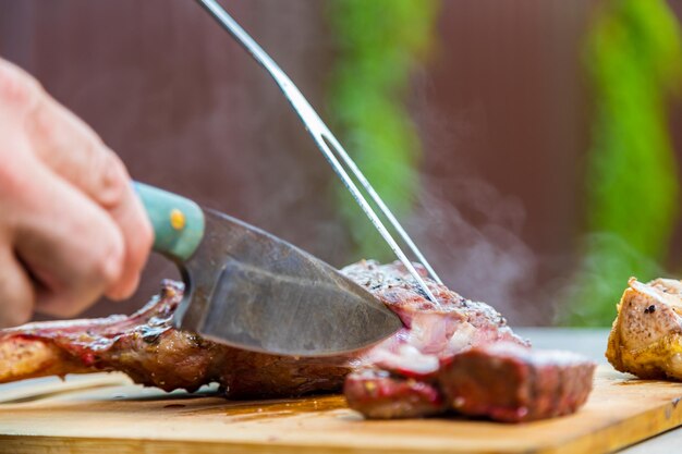 Um homem corta carne frita cozida em uma tábua de corte de carne cozida no forno para o jantar