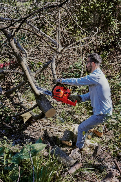 Um homem corta uma árvore caída com uma serra elétrica.