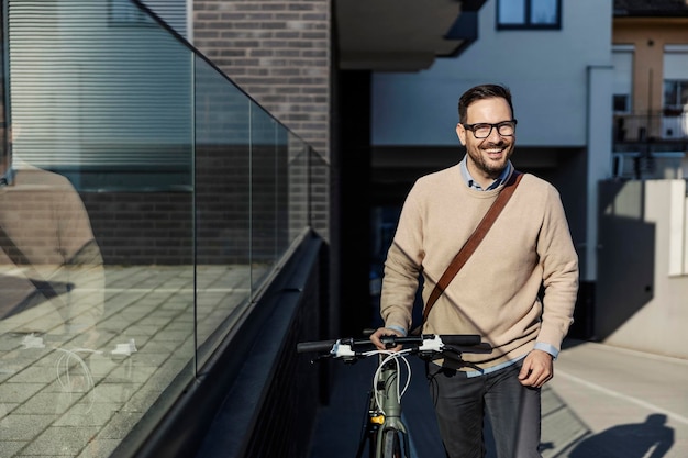 Um homem da moda empurrando uma bicicleta na rua da cidade