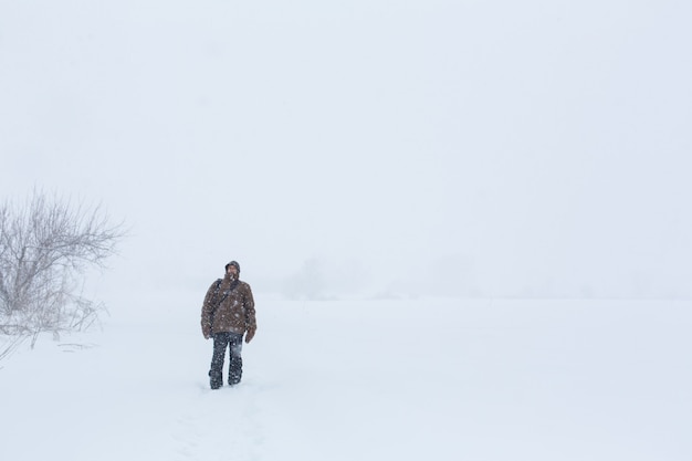 Um homem da vila caminha no inverno no campo. Nevasca de neve.