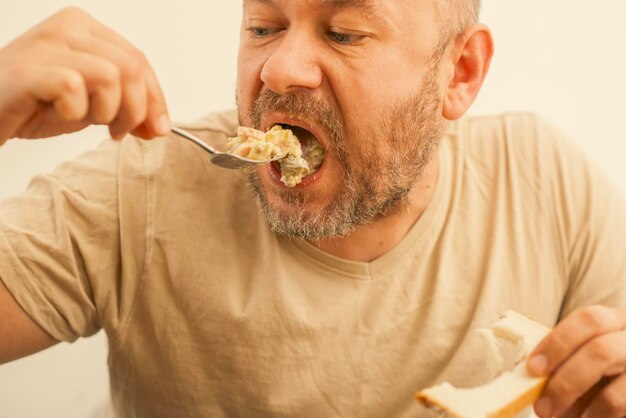 Um homem de 43 anos almoça com um garfo na mesa.