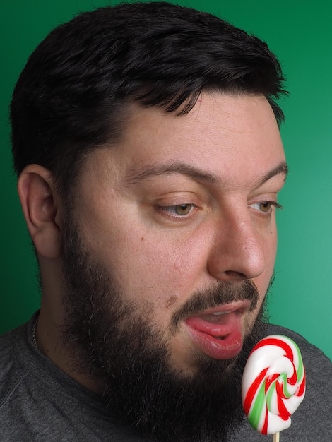 Um homem de barba comendo um pirulito com a palavra doce.