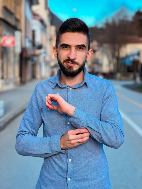 Um homem de camisa azul fica na rua e veste uma camisa azul.