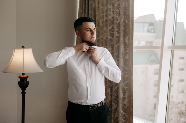 Foto um homem de camisa branca está ajustando sua gravata.