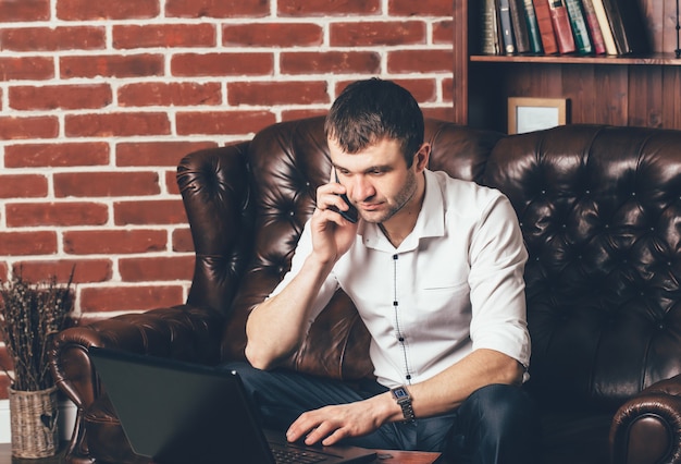 Um homem de camisa branca fala ao telefone.