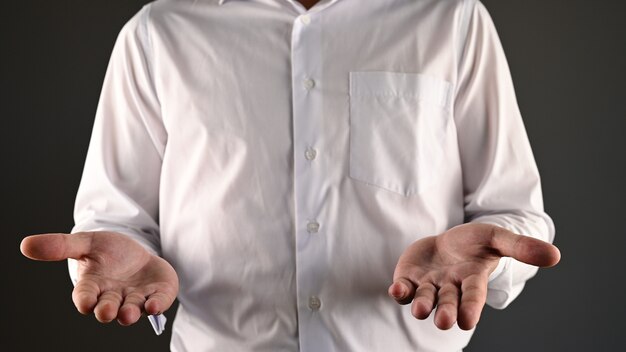 Um homem de camisa branca faz um gesto impotente.