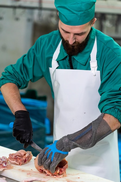 Um homem de camisa verde está cortando um pedaço de peixe com uma faca.