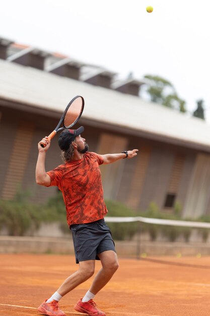 Um homem de camisa vermelha a jogar ténis