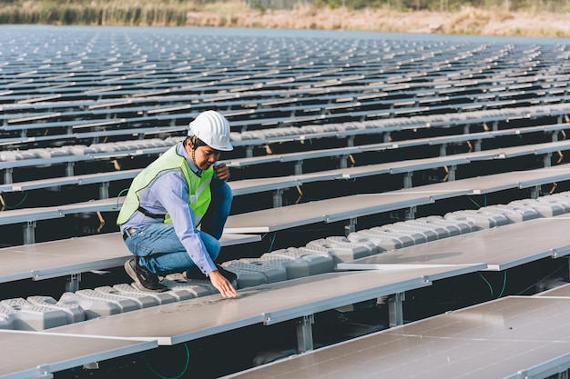 Um homem de capacete e colete verde está olhando para um painel solar em um campo.