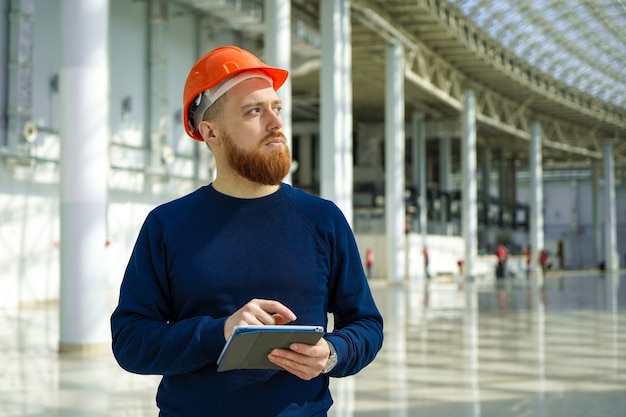 Um homem de capacete em um grande espaço com um tablet