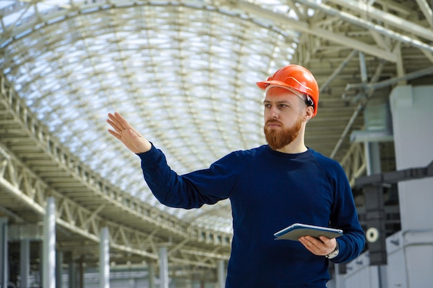 Um homem de capacete em um grande espaço com um tablet