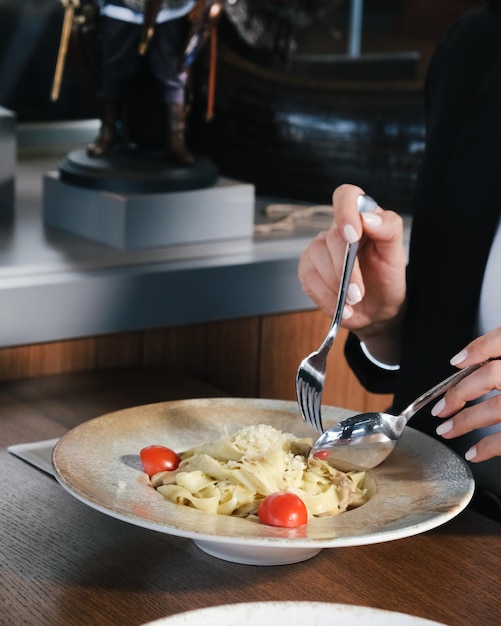 Um homem de fato está comendo macarrão com um garfo e um prato de macarrão
