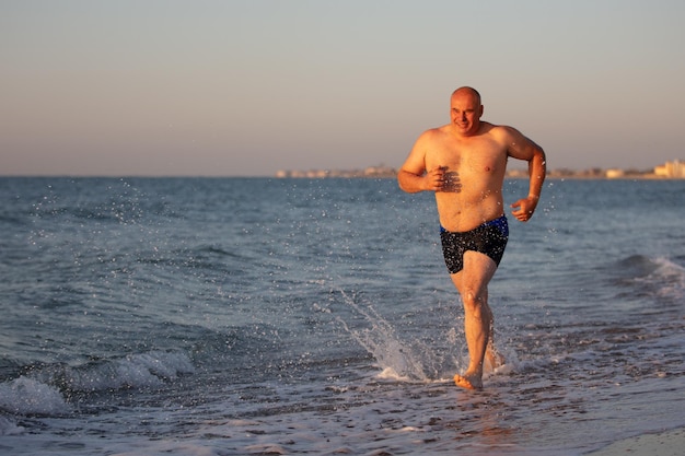 Um homem de meia-idade corre à beira-mar